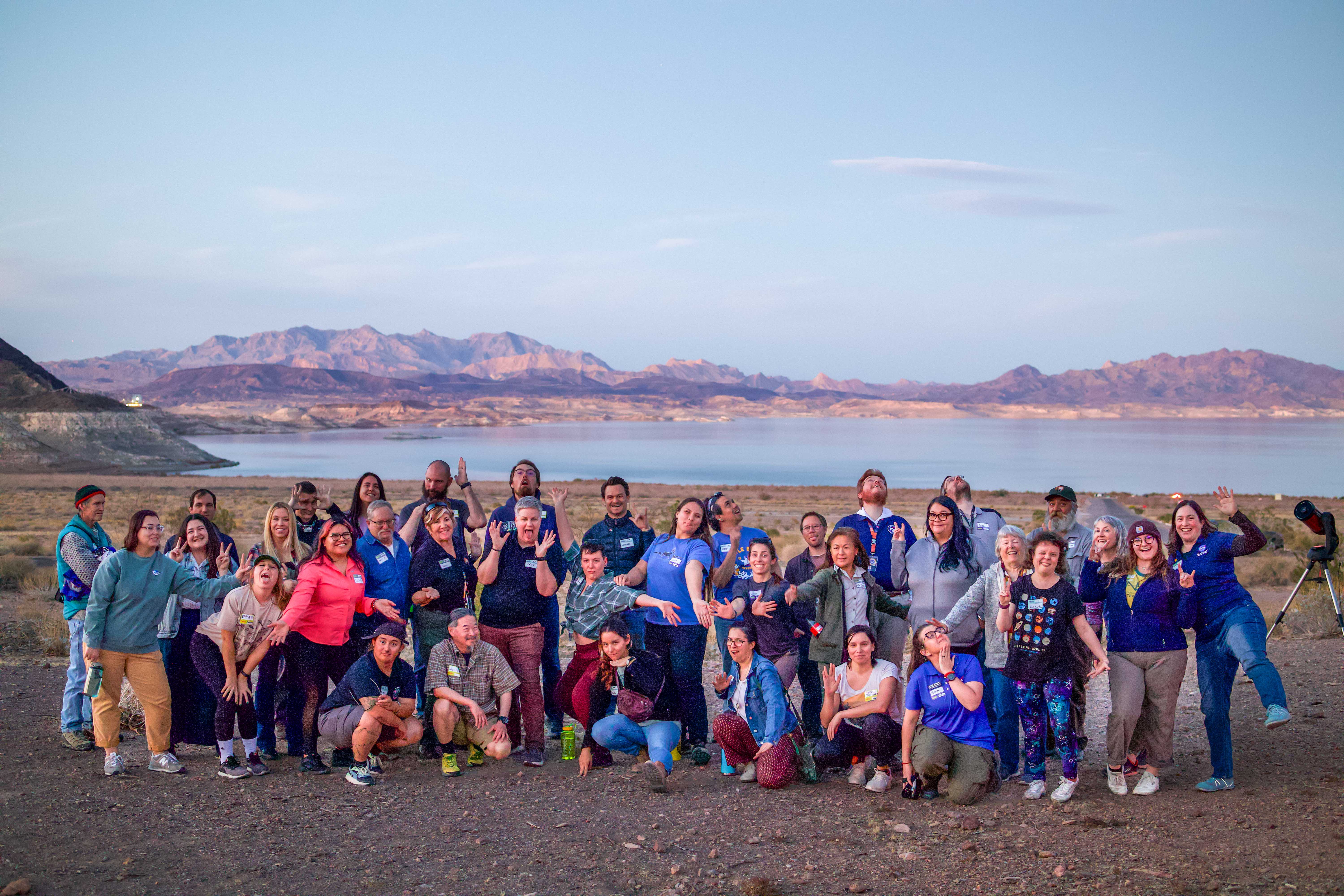 Earth to Sky participants posing together outdoors near a lake and mountains